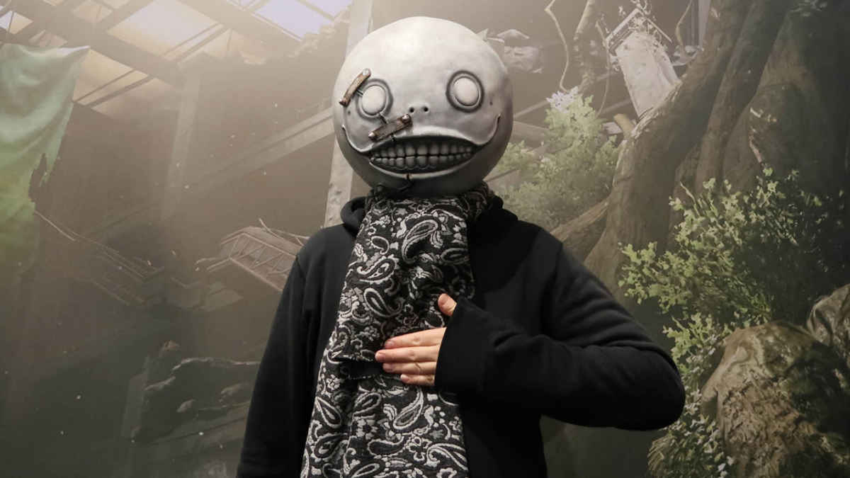 Fotografia che ritrae il famoso ed eccentrico game director Yoko Taro, con in testa l'iconica maschera di Emil